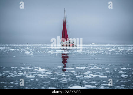 Ein kleines Schiff zwischen Eisbergen. Segelboot Kreuzfahrt unter schwimmende Eisberge in der Diskobucht Gletscher Mitternachtssonne Ilulissat, Grönland. Studium der Ph Stockfoto