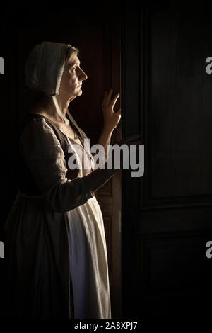 Frau warten an der Tür in der Dunkelheit Stockfoto