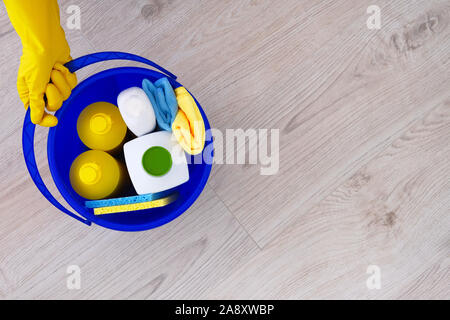 Reinigungsmittel in Plastikflaschen, Schwämme, Pinsel in blau Haushalt Eimer mit kopieren. Hand in gelben Gummihandschuh. Ansicht von oben. Close Up. Stockfoto