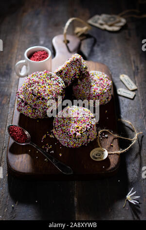 Kekse getränkt mit Schokoladensauce und sprengte mit bunten Süßigkeiten essen Stockfoto
