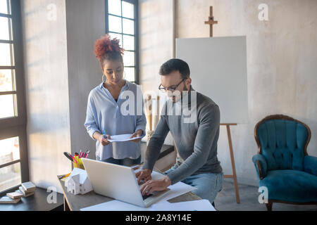 Interior Designer im Gespräch mit Staatssekretär während der Arbeit am Laptop Stockfoto