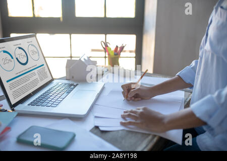 Designer Skizzen und Lesen von Nachrichten auf dem Laptop Stockfoto