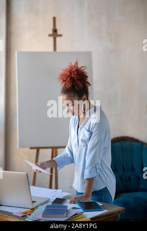 Curly Innenarchitekt Lesen von Dokumenten in der Nähe von Tabelle Stockfoto