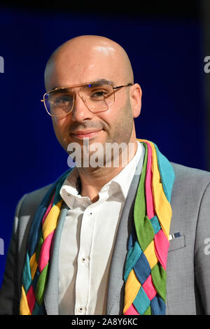 Konstanz, Deutschland. 04 Nov, 2019. Mohamed El Bachiri steht auf der Bühne im Konzil Gebäude nach der Vergabe des Konstanzer Konzilspreis. Um den Hals trägt er den Flügel als ein Zeichen für die Vergabe des Preises. Credit: Felix Kästle/dpa/Alamy leben Nachrichten Stockfoto