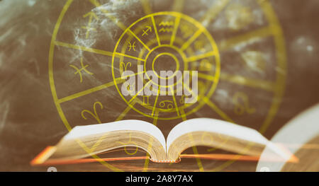 Astrologie und Horoskope Konzept. Buch und astrologischen Tierkreiszeichen Rad, abstrakten Hintergrund geöffnet. Stockfoto