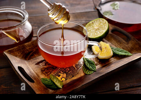 Gießen Honig in die Tasse Tee auf Holzboden im rustikalen Stil Stockfoto