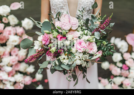 Woman Holding in den Händen große Hochzeit Blumenstrauß im rustikalen Stil. Die Grünen, rosa und weißen Rosen, coral Anthurium. Pastellfarben. Stockfoto