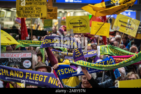 11 November 2019, Hessen, Frankfurt/Main: Demonstranten stehen am 300 Montag Demonstration der Fluglärm Demonstranten im Terminal 1 des Frankfurter Flughafens. Zu Beginn der Kampagne 'Detschland fliegt nicht "die Teilnehmer halten Schals und Poster. Foto: Frank Rumpenhorst/dpa Stockfoto