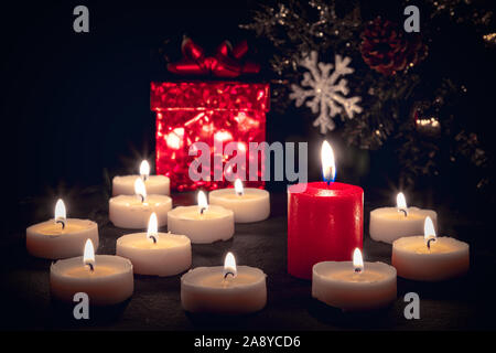 Weihnachten Kerzen brennen in der Nacht vor einer roten Geschenkverpackung Stockfoto