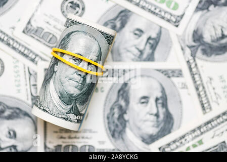 Eine Rolle von 100 Dollar-Scheine close-up auf einem Stapel der Amerikanische Dollar. Von Banknoten von 100 amerikanischen Dollar Hintergrund. Das Finanzkonzept. Stockfoto