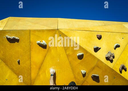 Junger Mann greift, um zu versuchen, Klettern an einer Kletterwand im Freien in einem Park in Valencia. Stockfoto