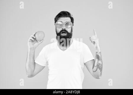 Gesunde orange Rezept Idee. Hipster mit Genius Idee Zeigefinger auf gelben Hintergrund. Bärtiger Mann erhielt glänzende Idee für natürliche Diät. Super Essen Idee. Stockfoto