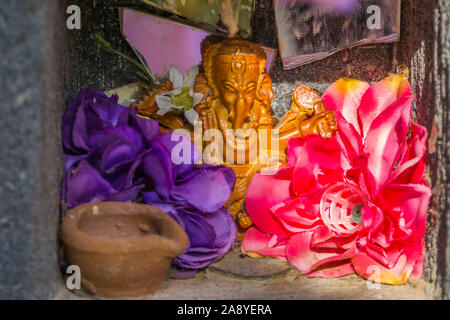 Schönen kleinen indischen Altar mit Blumen und einem Ganesha Skulptur, religiösen Hintergrund Stockfoto