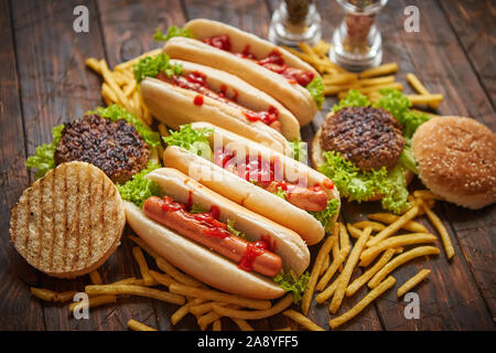 Fast Food Sortiment. Hamburger und Hot Dogs auf rostigen Holz Tisch Stockfoto