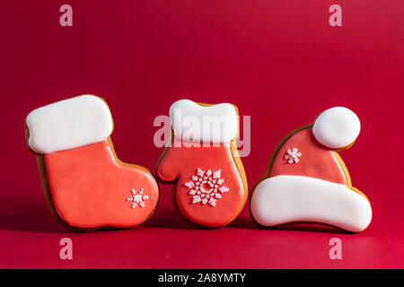 Lebkuchen Cookie von Santas Kleidung auf roten Hintergrund. Traditionelle Weihnachten essen. Weihnachten und Neujahr Urlaub Konzept Stockfoto