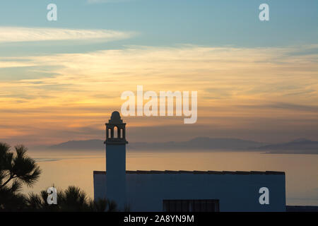 Ein traditionelles Haus mit verzierten Kamin ist gegen den Sonnenuntergang auf der Punta de la Mona über La Herradura Bay in Almuñécar, Spanien suchen. Stockfoto