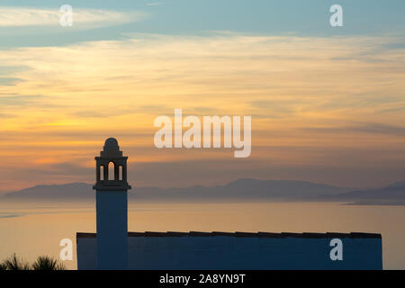 Ein traditionelles Haus mit verzierten Kamin ist gegen den Sonnenuntergang auf der Punta de la Mona über La Herradura Bay in Almuñécar, Spanien suchen. Stockfoto