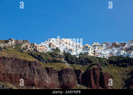 Wie von unten gesehen. An einem sonnigen Morgen liegt eine weiß getünchte Stadt auf einem Hügel auf der beliebten Insel Santorini. Auf den Kykladen der griechischen Inseln. Stockfoto