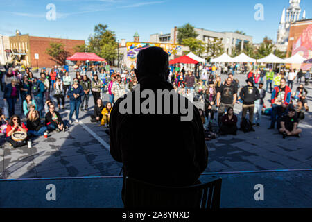 Silhouette von Mann zu Gast im öffentlichen Raum. Die Leute stehen und sitzen Zuhören im Hintergrund zu Lider. Klimawandel Protest Stockfoto