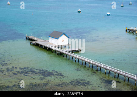 Lange Seebrücke mit Weißen in türkis Flachwasser und angelegten Boote Schuppen in der Nähe Stockfoto