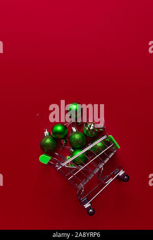 Eine kleine Katze von einem Supermarkt mit grünen Weihnachten Spielzeug gefüllt liegt auf einem roten Hintergrund. Spielzeug Bekommen wir genügend Schlaf von einem Korb. Handel anhand von quantitativen Simulatio Stockfoto