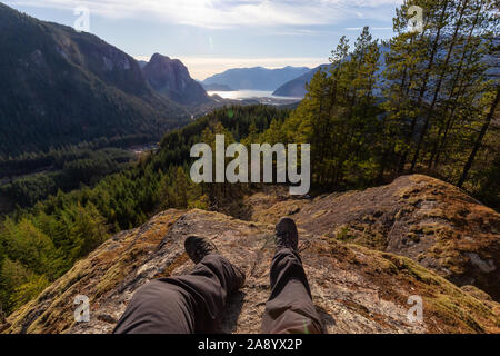 Das Sitzen auf dem Rand einer Klippe und genießen die schönen kanadischen Bergwelt Aussicht an einem sonnigen Abend. In Squamish, nördlich von Vancouv genommen Stockfoto