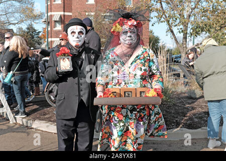 Ein paar in bunten skull Make up und Maske feiern Dia de los Muertos in Cleveland, Ohio, USA halten momentos von Lieben, die weitergegeben. Stockfoto
