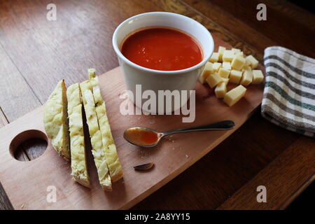 Köstliche Schale Tomaten Suppe bereit, mit Löffel, Brot und Käse. Durch Tageslicht erhellt. Stockfoto