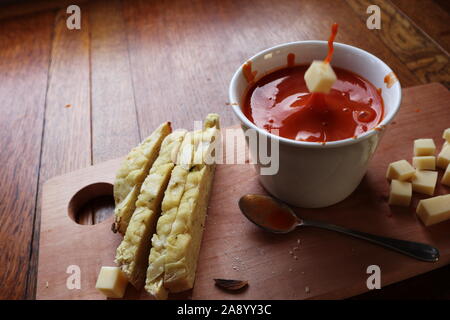 Käse cube in Tomatensuppe, die in einer weißen Schüssel und machen eine unordentliche Splash mit mehr Käsewürfel auf der Seite und Focaccia Scheiben Brot Stockfoto