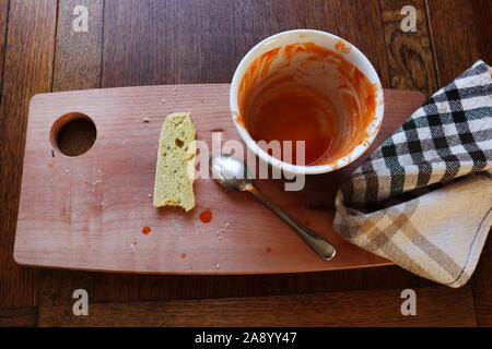 Leere Schüssel mit den Überresten von Tomatensuppe, Löffel, ein wenig Brot und eine Serviette Stockfoto