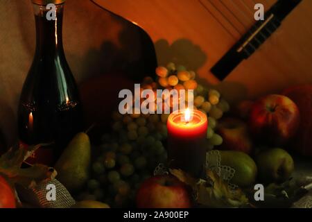 Herbst warm Szene. Noch Leben ernten. Thanksgiving post card Grüße. Kerze mit reifen Früchten und einer Flasche Wein. Stockfoto