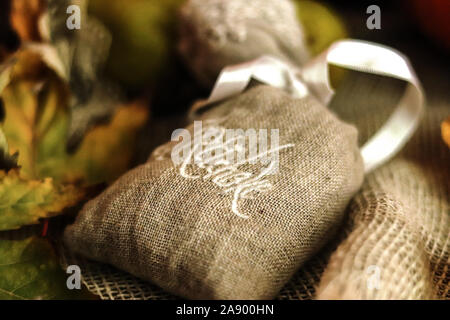 Artischocke Kräuter in einem kleinen Leinensack mit Spitze Band und hinterlässt einen Sack Hintergrund. Close Up. Soft Focus Stockfoto