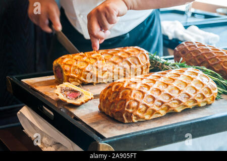 Ein Koch das Schnitzen eines Beef Wellington Rossini als bei einem Mittagessen in der puli Phenix Restaurant serviert. Stockfoto