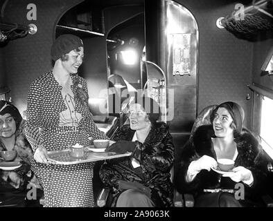 Miss Wanda Holz, Gastgeberin für die Eastern Air Transport, serviert Tee für zwei, vermißt Charlotte Childress und Elizabeth Hume, an Bord eines der passagiermaschinen der Linie Ca. 1930 Stockfoto