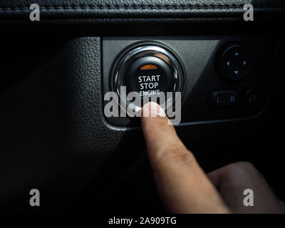 Durch Drücken der Start-Stop-Taste Motor mit orange Licht auf Schwarze Auto konsole Hintergrund. Stockfoto