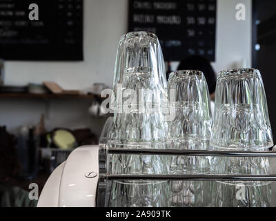 Stapel sauber leere Gläser auf Edelstahl Regal im Cafe. Stapel von oben nach unten Trinkwasser Gläser. Stockfoto