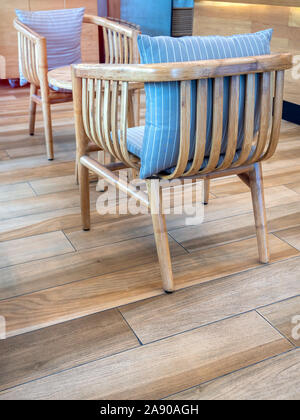 Stühle aus Holz mit blauen Kissen und Holz- Runder Tisch über Holzboden vertikale Stil. Stockfoto