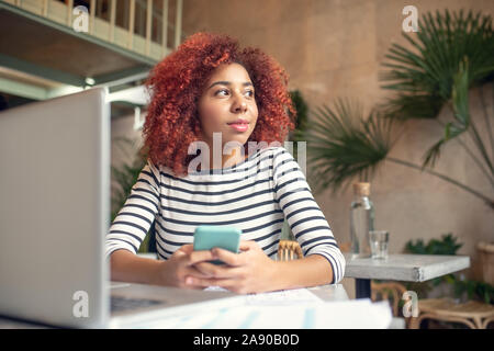 Junge Frau mit Telefon, während Sms ihr Freund Stockfoto