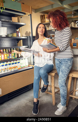 Junge Unternehmerinnen diskutieren Getränke in der Cafeteria Stockfoto