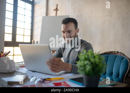 Gut aussehender Geschäftsmann auf Laptop am Wochenende arbeiten Stockfoto