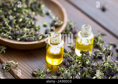 Thymianöl Flaschen mit getrockneten Thymian Pflanzen und Blumen auf hölzernen Hintergrund Stockfoto