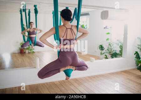Antenne antigravity yoga Konzept. Frau fliegen Üben Yoga in Schwerelosigkeit Yoga Studio mit grün Hängematte. Stockfoto