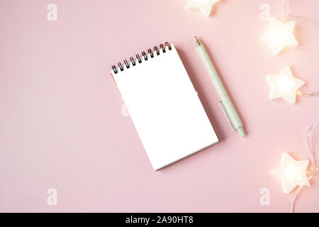 Weiße Notebook Blatt auf rosa Hintergrund mit Girlande Stockfoto