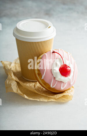 Glasierte Krapfen mit Sahnehäubchen und Kaffee, die Sie mitnehmen Stockfoto