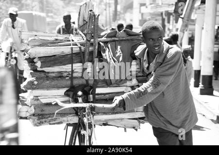 Rift Valley: Ein junger Mann, der Holz auf seinem Fahrrad durch die Straßen der Stadt Eldoret Stockfoto