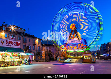 Beleuchtete Karussell und mobile mit Süßigkeiten am Stadtplatz in Abend in Alba, Italien. Stockfoto