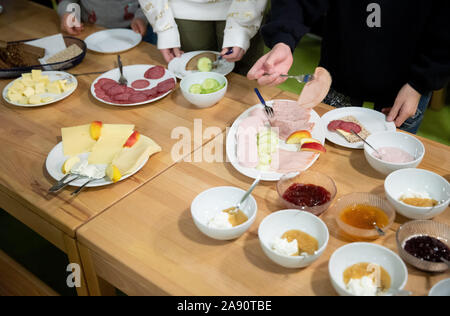 12 November 2019, Hamburg: Grundschule Kinder helfen, sich selbst das Essen im Brüder Grimm Schule in Hamburg-Billstedt während der Schule Frühstück 'Brotzeit'. Laut der Vereinigung, die die Schauspielerin Uschi Glas mit ihrem Ehemann in 2009 gegründet, 'Brotzeit' organisiert täglich ein Frühstück bieten mit Schulen, Freiwillige und der Lebensmittelindustrie an 210 Schulen im ganzen Land. Foto: Christian Charisius/dpa Stockfoto