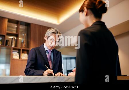 Senior Geschäftsmann einchecken im Hotel Stockfoto