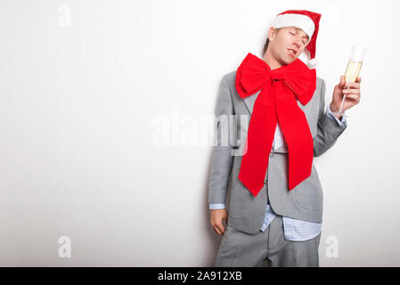 Betrunken Büro in Santa Hut und einem grossen roten Bogen gegen die Wand lehnte sich für einen Rest nach zu viel Party Stockfoto