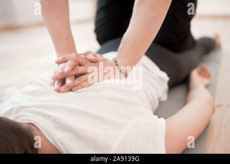 Mann ist zurück der Frau Massage im weißen T-Shirt liegen auf grauem Teppich in der Turnhalle Stockfoto